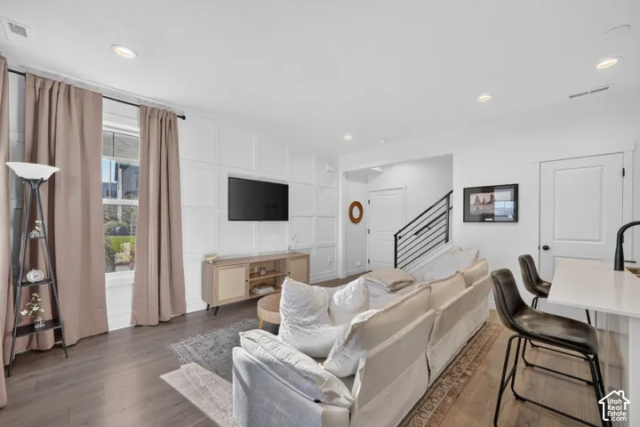 Open-concept living area featuring a decorative accent wall, recessed lighting, and wood-finish flooring