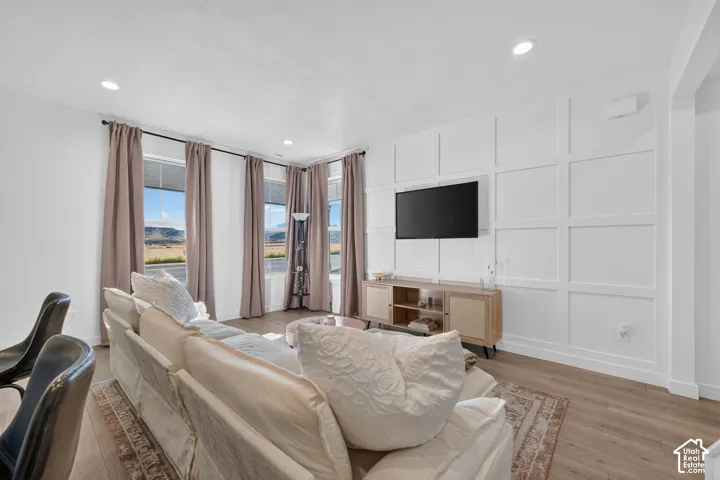 Wood-finish flooring, recessed lighting, and a feature wall with decorative paneling