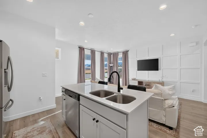 Kitchen island with dual stainless steel sinks, a matte black faucet, and light-toned countertops