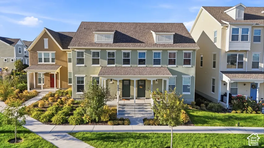 Pitched roofline with dormer windows, covered front porches, and established landscaping