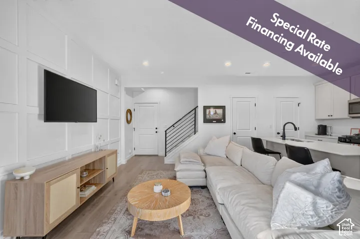 Interior space featuring white board-and-batten accent wall, wood-finish flooring, recessed lighting, and kitchen island with matte black faucet