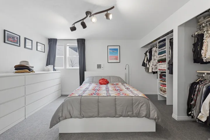 Recessed window, track lighting fixture, built-in open closet system, and gray carpet flooring