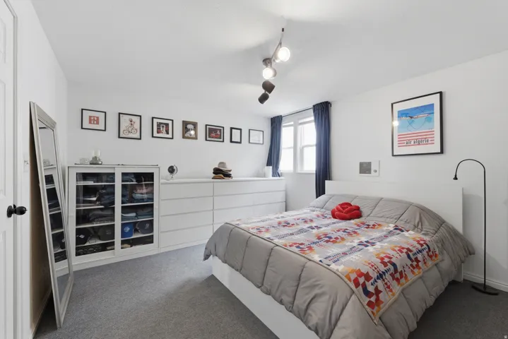 Carpeted flooring, window with dark drapes, track lighting, and a white door with black hardware