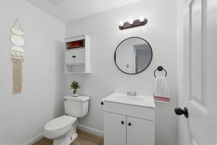 White vanity with integrated sink, modern round mirror, and wall-mounted light fixture