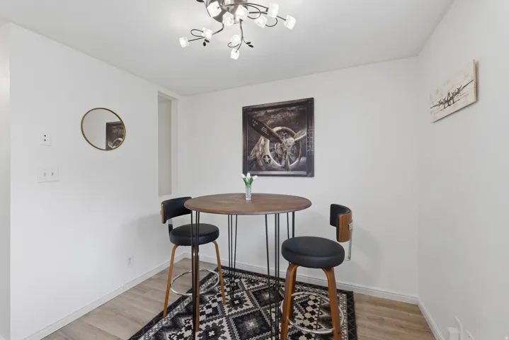 Wood-finish flooring with a modern ceiling light fixture and white painted walls