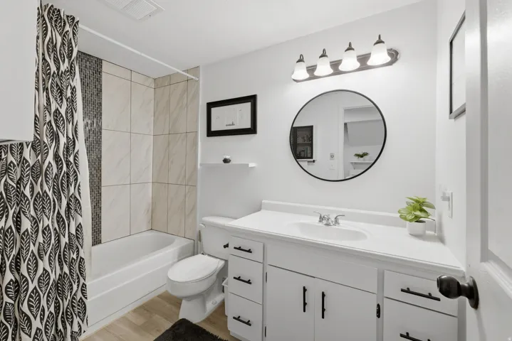 White vanity with black hardware, integrated sink, and wall-mounted light fixture