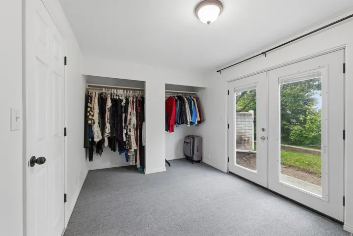 French doors leading to an exterior area, two built-in closet spaces, and gray carpet flooring