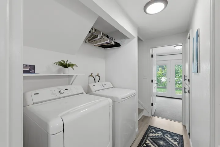 Laundry area featuring wood-finish flooring, a wall-mounted shelf, and an overhead storage rack