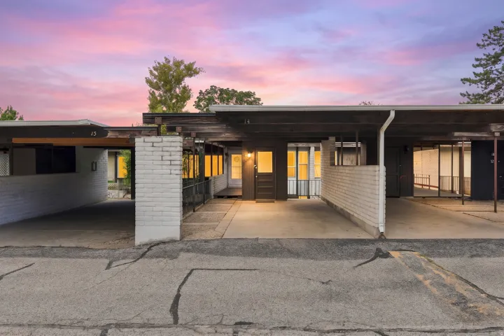 Front exterior with two covered carport parking spaces, white brick accents, and a dark wood-finish fascia