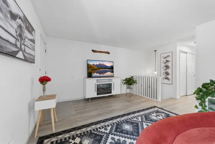 Light-toned wood-finish flooring, white walls, and a white railing with vertical spindles