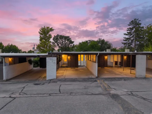 Multi-unit property featuring covered carport parking, white brick accents, and individual entryways
