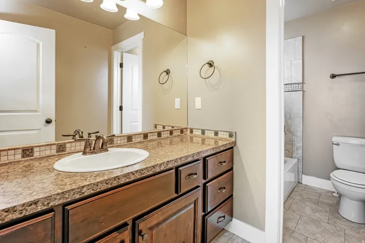 Vanity with an integrated sink, a mosaic tile backsplash, a bronze-finish faucet, and coordinating hardware