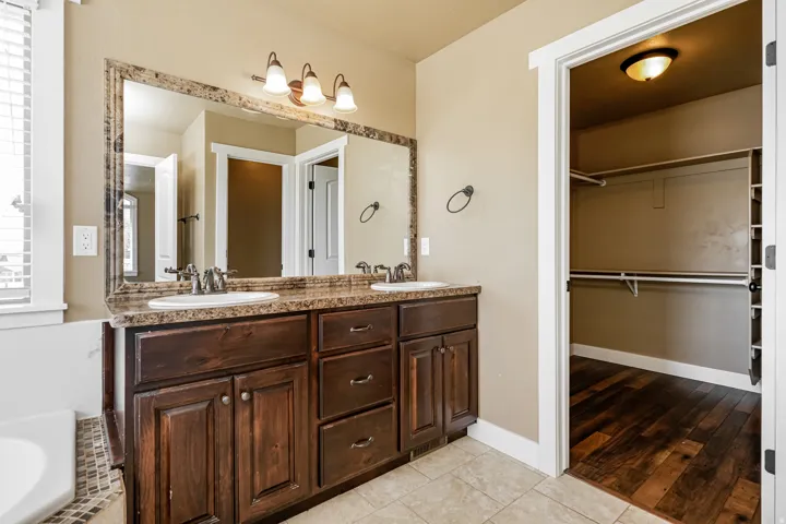 Dual vanity with dark wood-finish cabinetry, integrated sinks, and a large framed mirror