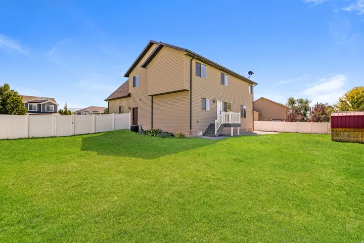 Spacious backyard with a vibrant lawn, privacy fencing, and a built-in deck with stairs