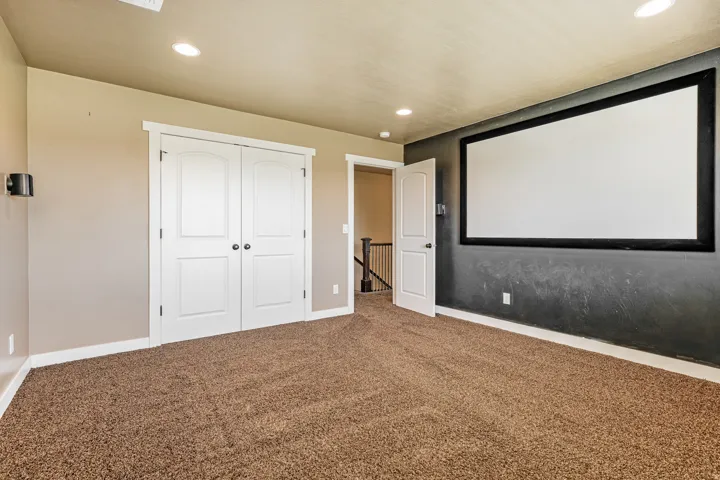 Built-in projector screen, wall-mounted speaker, recessed lighting, and carpet flooring