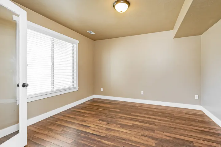 Room featuring wood-finish flooring, a large window with blinds, and recessed lighting