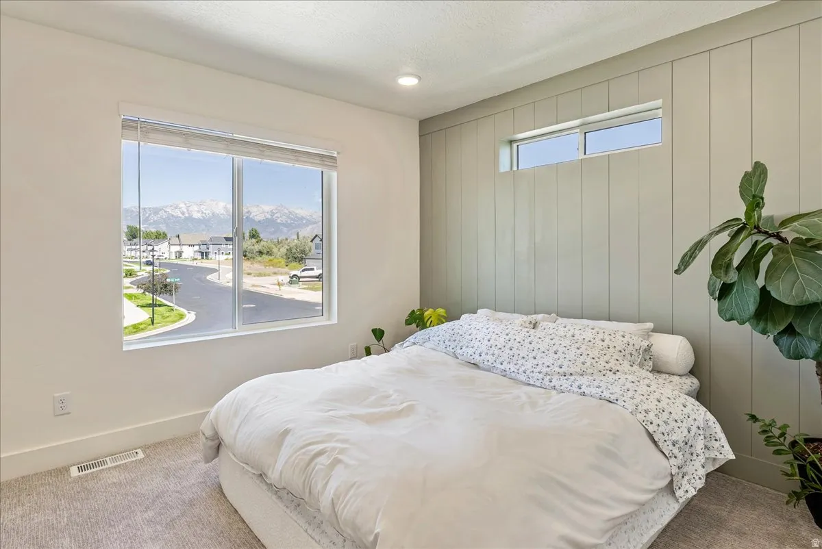 Expansive window with mountain scenery, recessed lighting, accent wall with vertical paneling, and a high transom window
