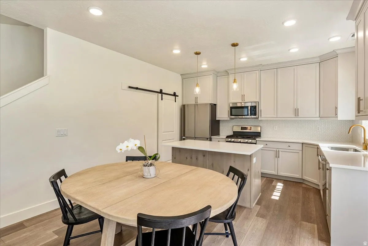 Kitchen featuring a center island with a white countertop, light gray cabinetry, stainless steel appliances, and a white tile backsplash