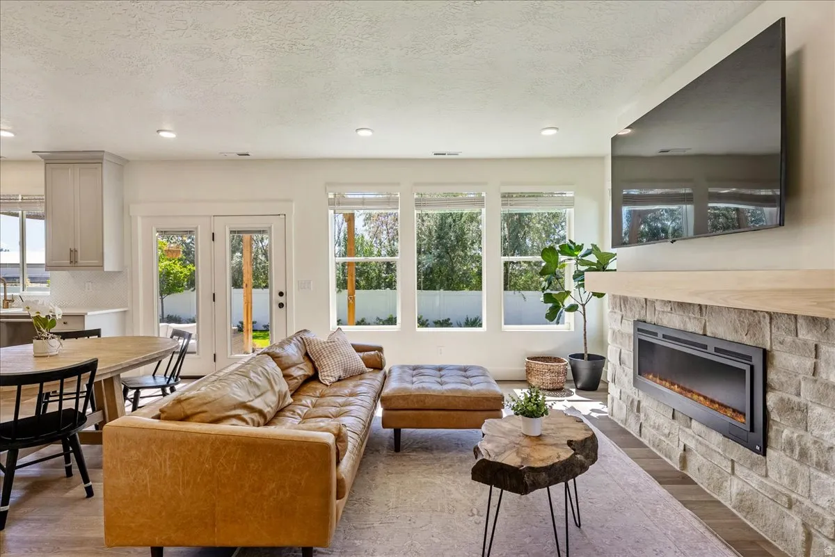 Recessed lighting, wood-finish flooring, and a stone-clad fireplace with a wood mantel
