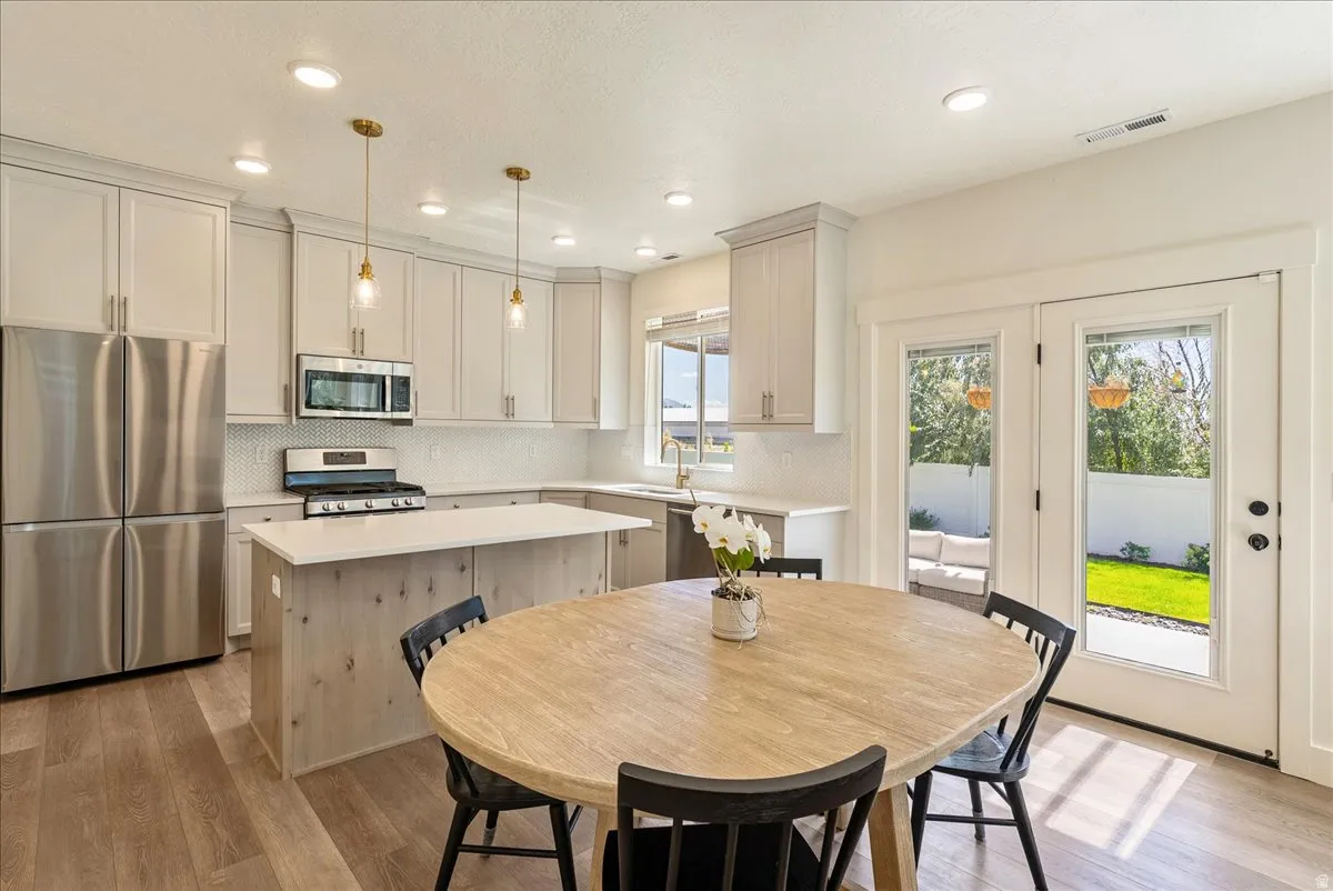 Kitchen featuring shaker-style cabinetry, stainless steel appliances, a center island with counter seating, and wood-finish flooring