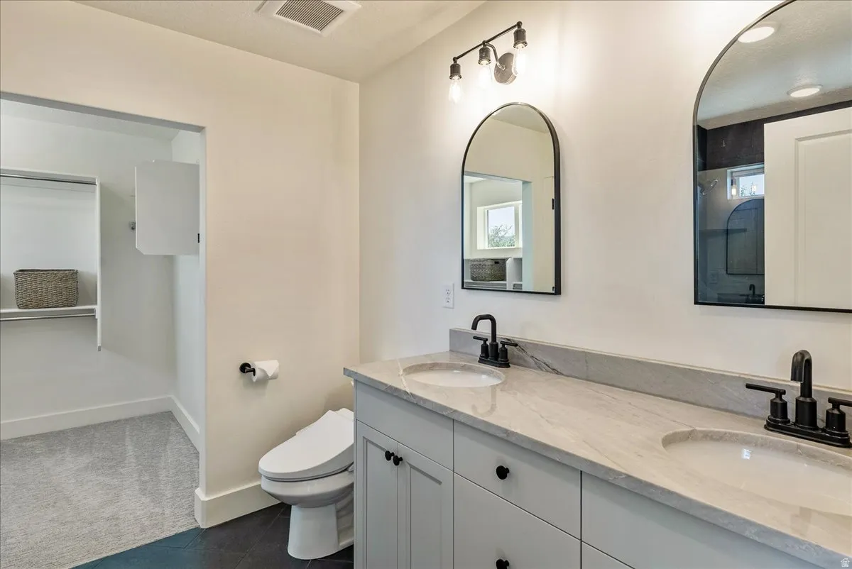 Dual arched mirrors, dual vanity sinks, light-colored countertop, matte black hardware, and built-in closet shelving