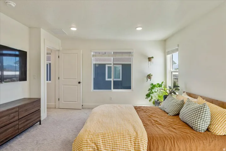 Carpeted flooring, recessed lighting, white interior doors, and multiple windows