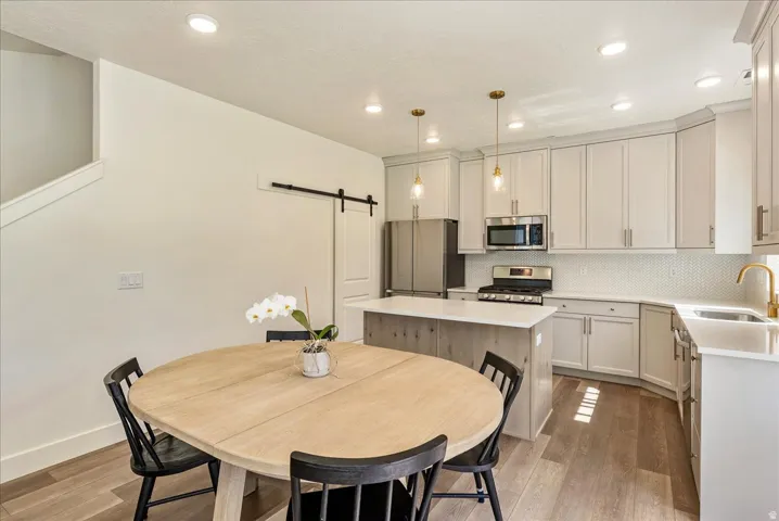 Kitchen featuring a center island with a white countertop, light gray cabinetry, stainless steel appliances, and a white tile backsplash