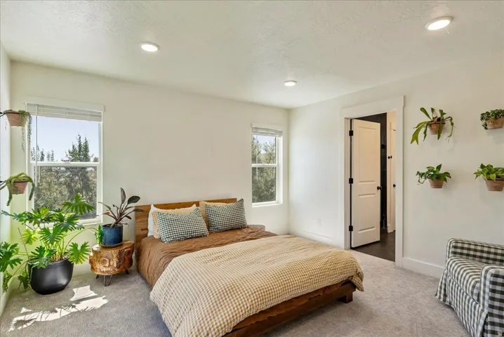 Light-filled room featuring recessed lighting, a neutral color palette, two windows with white blinds, and a white interior door with dark hardware