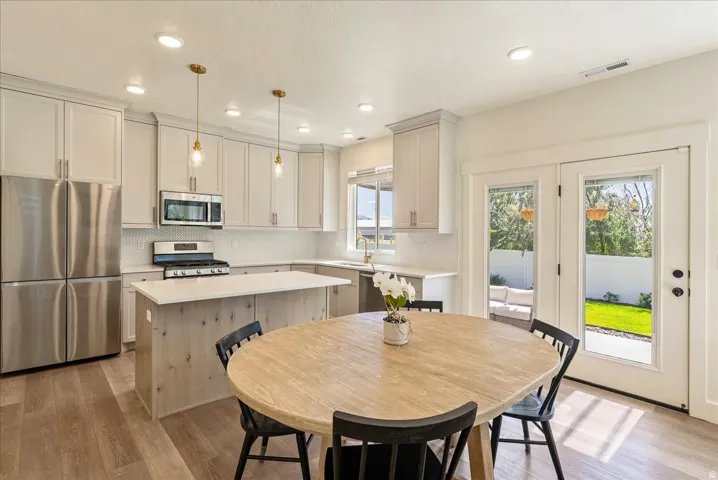 Kitchen featuring shaker-style cabinetry, stainless steel appliances, a center island with counter seating, and wood-finish flooring