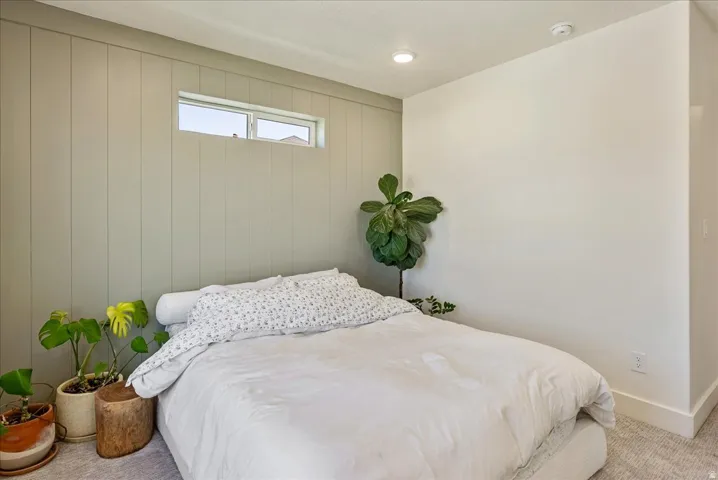 Paneled accent wall, recessed ceiling lighting, horizontal window, light-colored carpeting, and painted walls