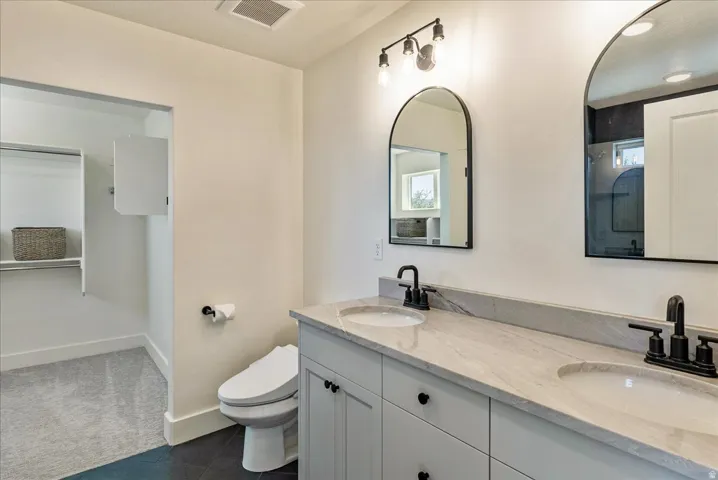 Dual arched mirrors, dual vanity sinks, light-colored countertop, matte black hardware, and built-in closet shelving