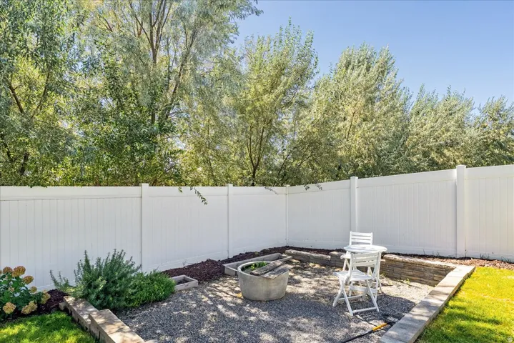 Private backyard space with white privacy fencing, gravel ground cover, and raised garden beds