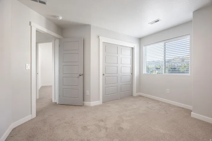 Neutral-toned carpeting, light gray walls, and white trim