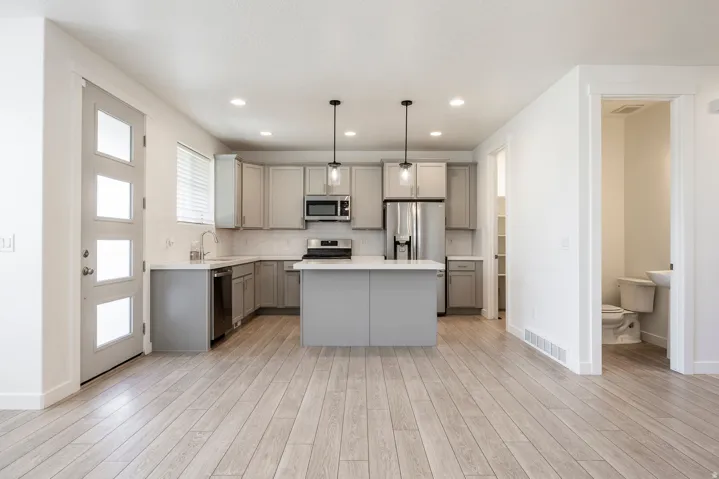 L-shaped kitchen with gray cabinetry, white countertops, and stainless steel appliances