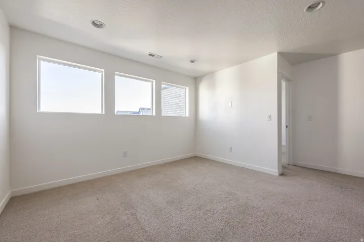 Recessed lighting, light-colored carpeting, multiple windows, white walls, and white trim