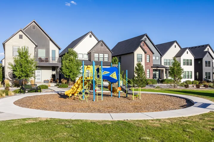 Contemporary residential architecture, community green space, integrated playground, paved walking path, and mature landscaping
