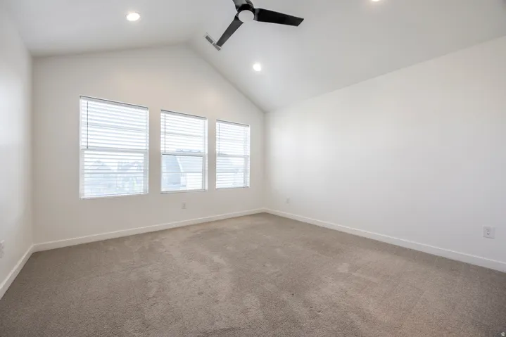 Vaulted ceiling featuring recessed lighting and a ceiling fan, three windows with blinds, and neutral carpeting