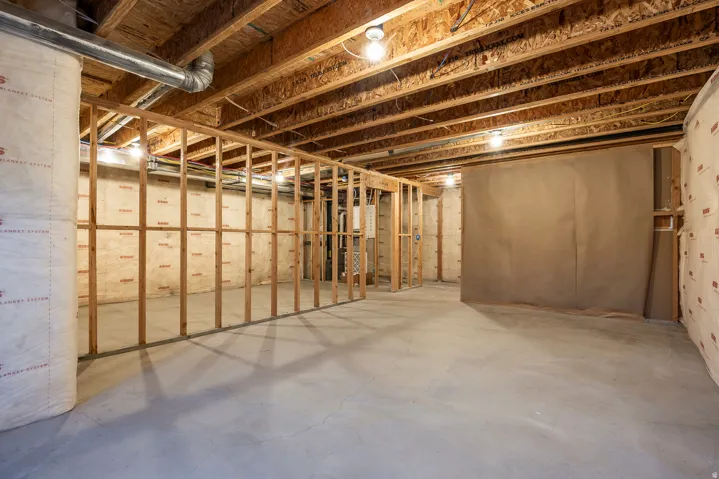 Unfinished basement with exposed ceiling joists, concrete flooring, and partial wall framing