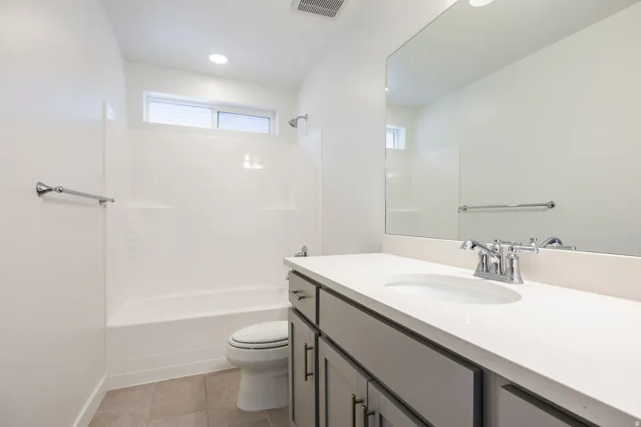 Bathroom with a bathtub, shower, and vanity featuring a countertop with an integrated sink