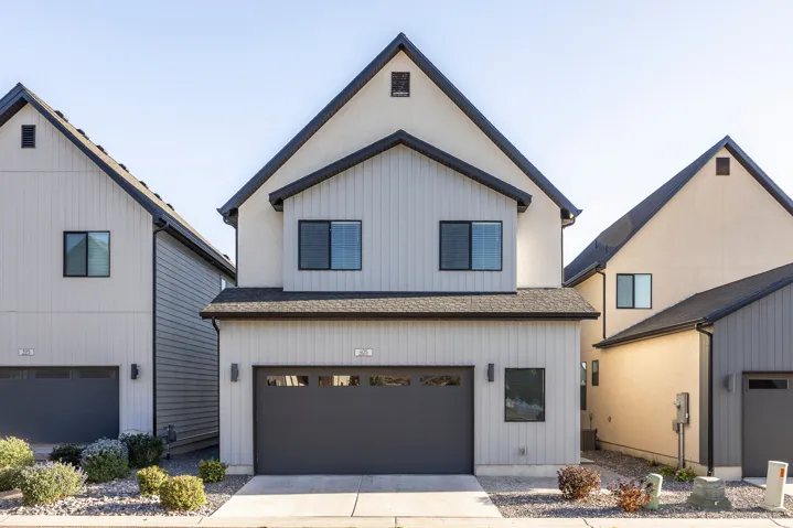 Contemporary two-story exterior with a gabled roofline, light-toned stucco and siding, and an integrated garage with a dark door