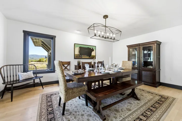 Hardwood flooring, dark trim window framing, dark trim baseboards, white walls, and a multi-light geometric chandelier