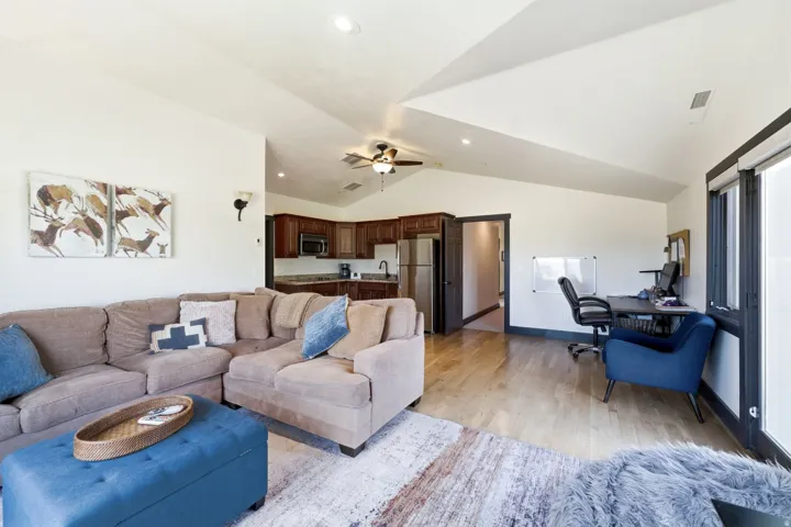 Vaulted ceiling, recessed lighting, wood-finish flooring, dark wood cabinetry, and stainless steel appliances