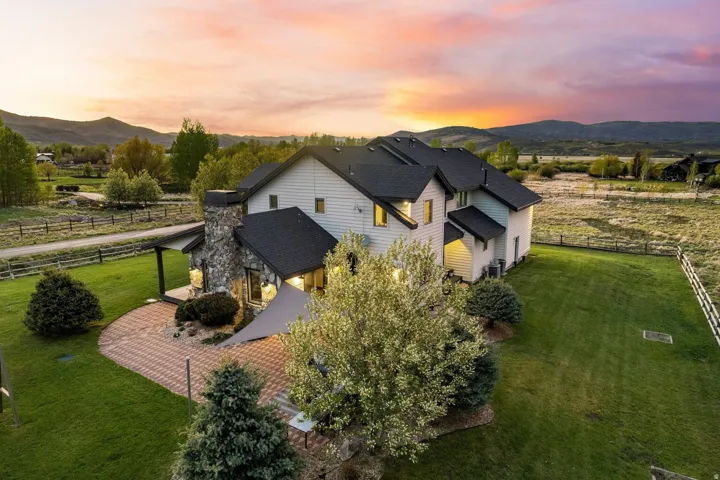 Contemporary residence with stone chimney, multi-level roofline, and expansive manicured lawn