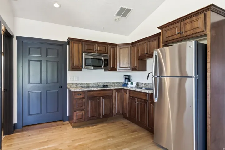 Kitchen featuring wood-finish flooring, dark wood cabinetry, stainless steel appliances, and light-toned countertops