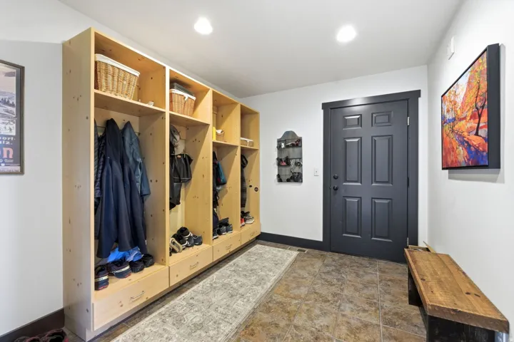 Entryway with built-in storage cubbies, recessed lighting, tile flooring, dark paneled door, and a wooden bench