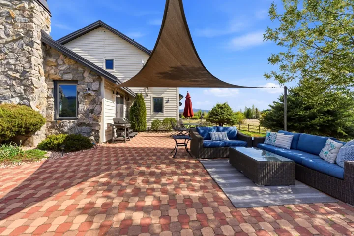 Stone and siding exterior with a paver patio and shade sail