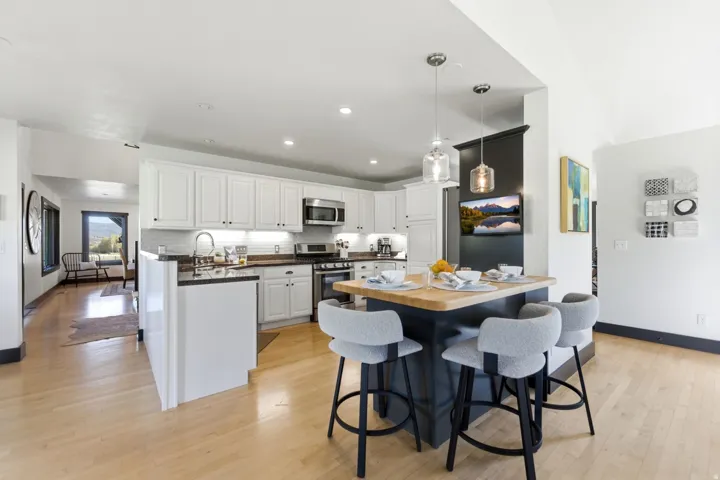 Kitchen featuring white cabinetry, stainless steel appliances, dark countertops, and a central island with a wood-finish top