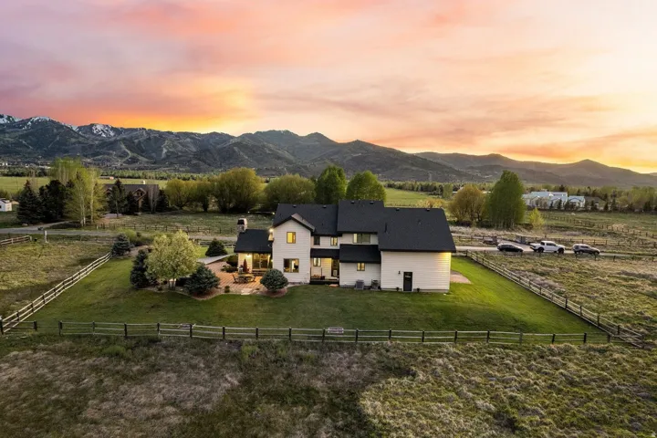 Expansive property featuring a multi-level structure with a dark-pitched roof, a stone patio, and a mountain backdrop