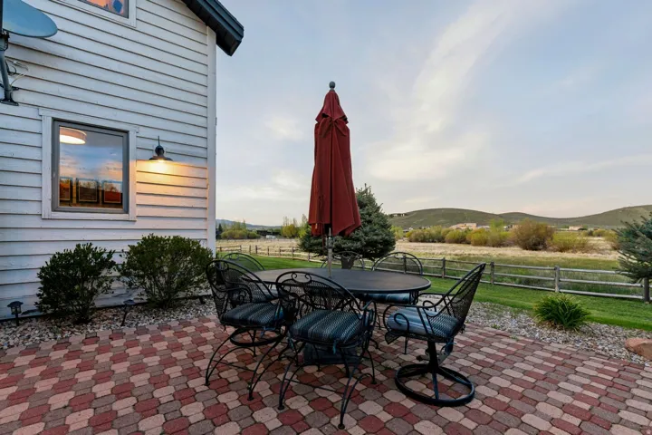 Paved patio with decorative pavers, exterior wall lighting, and natural scenery