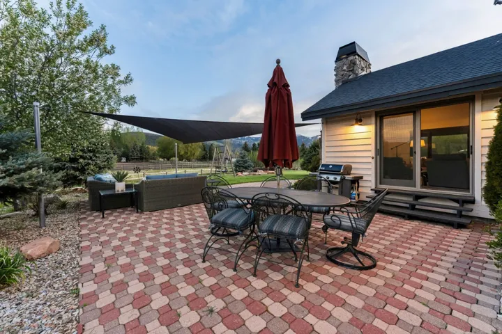 Paver patio with a sliding glass door entry, exterior lighting, and a stone chimney